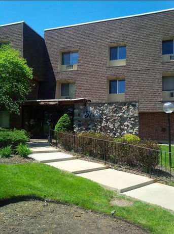 Front view of a multi-story brick building with a small entrance canopy.