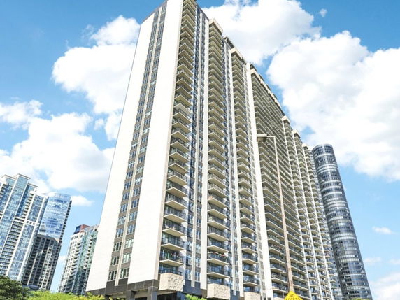 Front view of a tall residential building with multiple balconies.