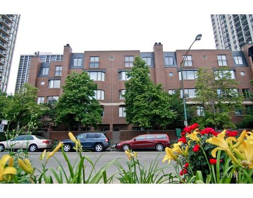 Front view of a multi-story brick building with surrounding trees and parked cars.