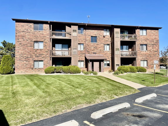 Front view of a three-story brick apartment building with balconies.