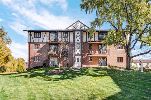 Front view of a multi-story brick apartment building with balconies and a central entrance.