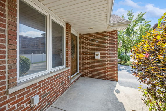 Front view of a house entrance with brick exterior and a covered porch.