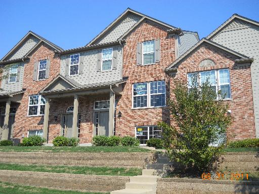 Front view of a multi-story brick townhouse with multiple entries.