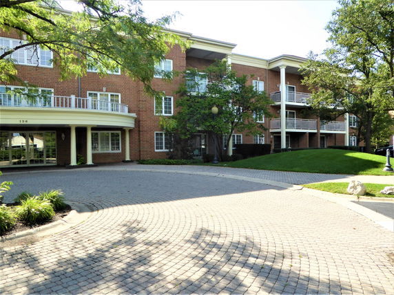 Front view of a three-story brick apartment building with balconies.
