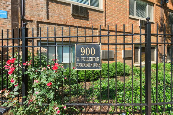 Front view of a brick condominium building with a black metal fence.