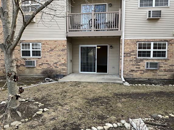 Front view of a house with brick and siding exterior, featuring a balcony and sliding glass door.
