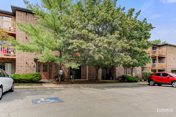 Front view of a brick apartment building with balconies and parking area.