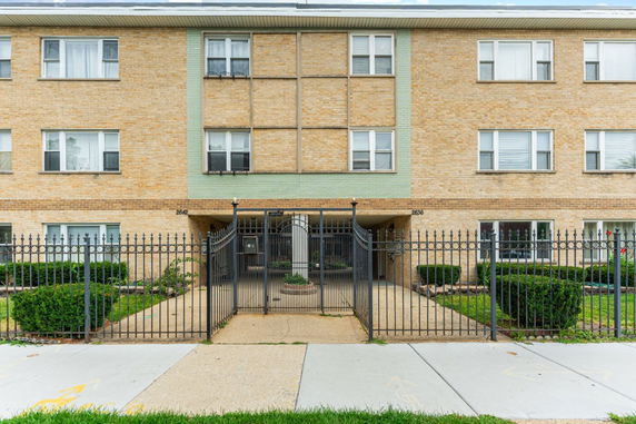 Front view of a multi-story brick apartment building with gated entrance.