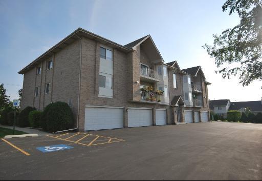 Front view of a multi-story brick building with multiple garages on the ground floor.