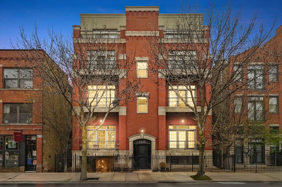 Front view of a multi-story brick building with illuminated windows.