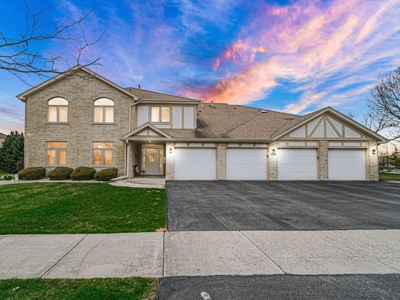 Front view of a large two-story house with a three-car garage and brick exterior.