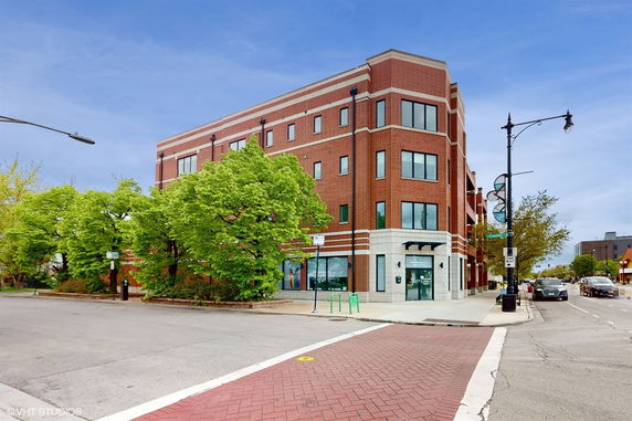 Front view of a multi-story brick building on a street corner.