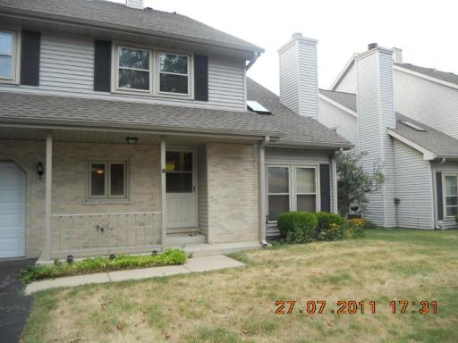 Front view of a two-story house with a small porch and attached garage.
