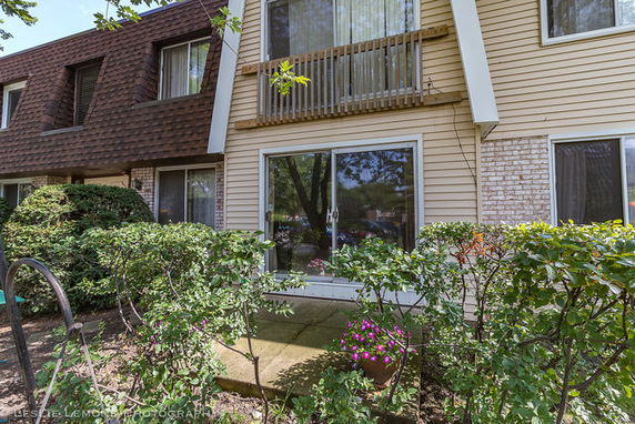 Front view of a two-story house with sliding doors and brick siding.
