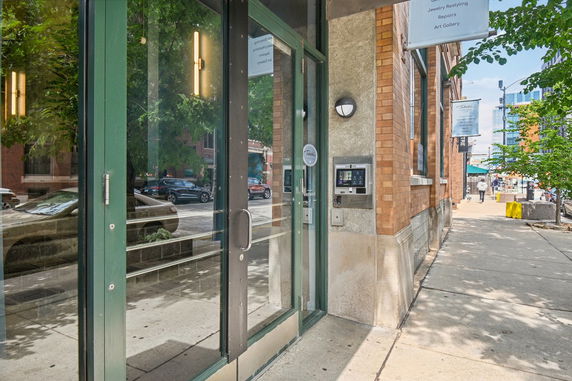 Entrance with glass doors and brick exterior of a building on a city street.