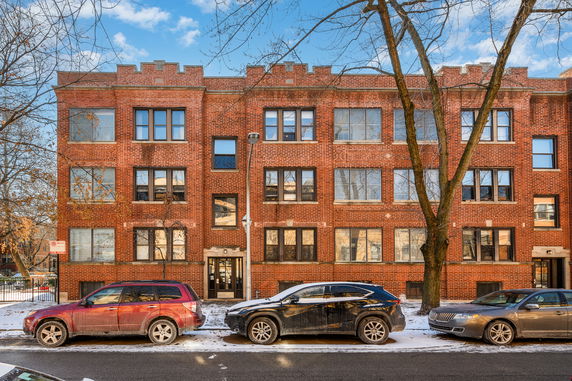 Front view of a three-story brick apartment building with large windows.