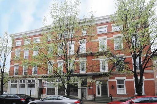 Front view of a multi-story red brick building with trees in front.
