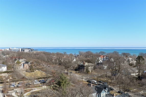 Panoramic view of a coastal town with residential houses and a large body of water in the distance.