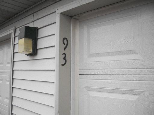 Close-up view of a house's exterior with a garage door and an outdoor light fixture.