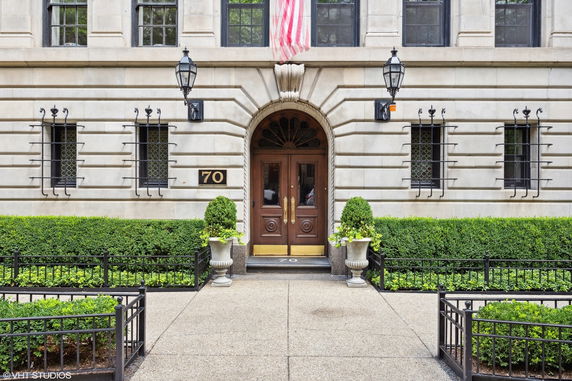 Front view of a building entrance with ornate wooden doors and an American flag above.