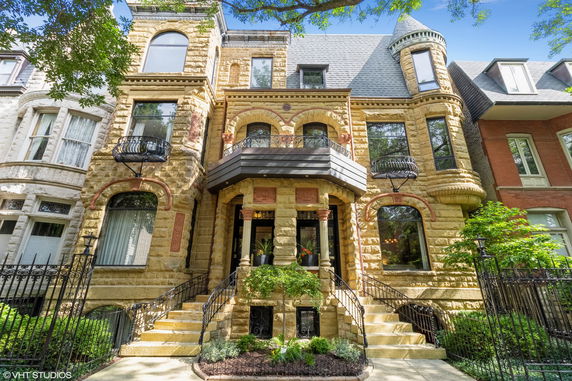 Front view of a historic multi-story building with stone facade and wrought iron railings.