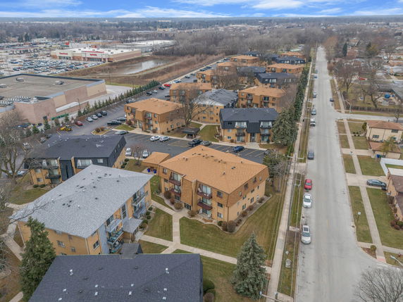 Aerial view of residential buildings and surrounding area with roads and parking lots.
