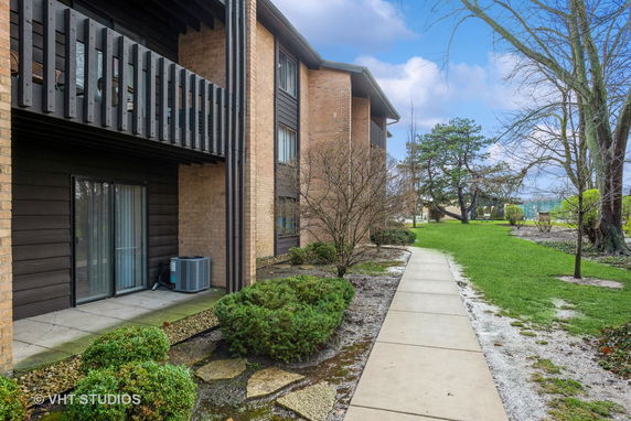 Front view of a multi-story apartment building with balconies and a walkway.