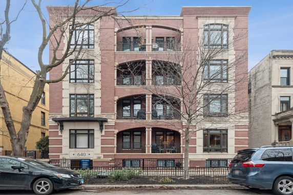 Front view of a multi-story brick apartment building with balconies.