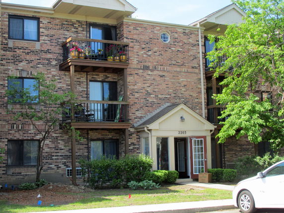 Front view of a multi-story brick apartment building with balconies.