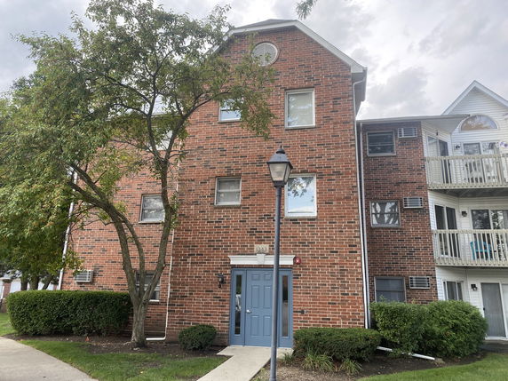 Front view of a multi-story brick apartment building with balconies.