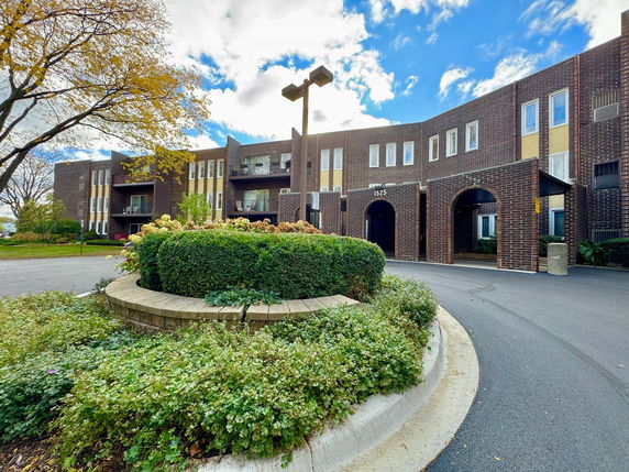 Front view of a brick apartment building with arched entrances.