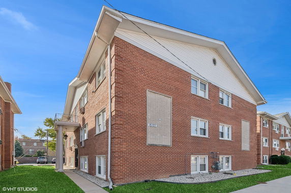 Front view of a two-story brick apartment building with a gabled roof.