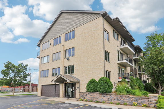 Front view of a multi-story brick apartment building with balconies.