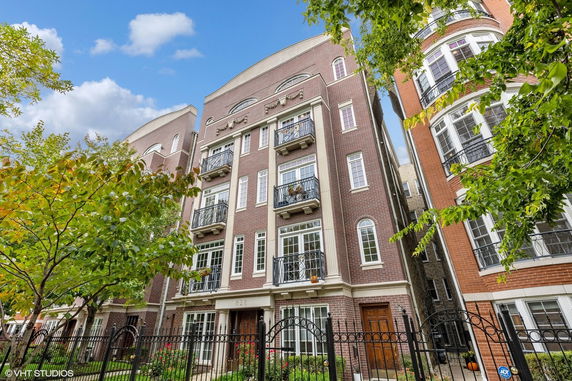 Front view of a multi-story brick apartment building with balconies and large windows.