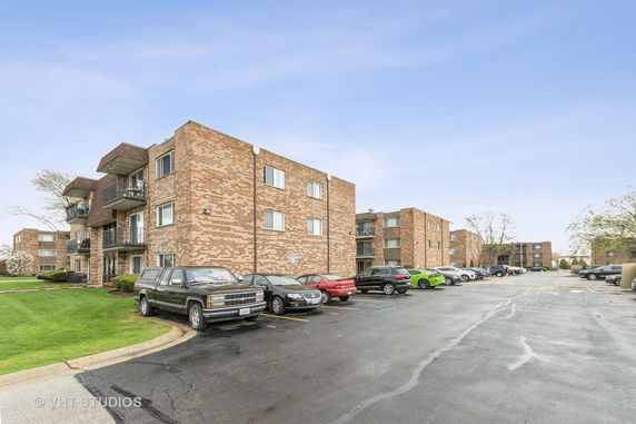 Front view of a multi-story brick apartment building with balconies.
