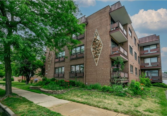 Front view of a multi-story brick apartment building with balconies.