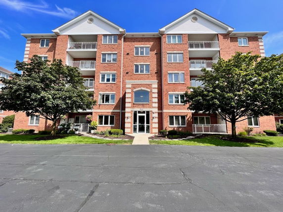 Front view of a multi-story brick apartment building with balconies.