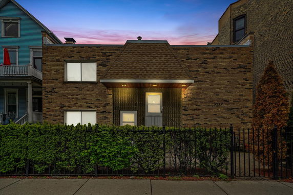 Front view of a brick house with a geometric facade and a small entrance area.