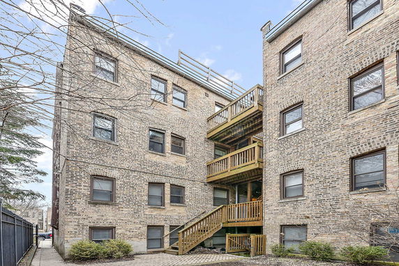Exterior view of a brick apartment building with multiple floors and wooden balconies.