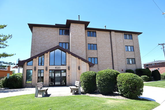 Front view of a multi-story brick building with large windows and a main entrance.