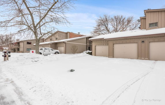 Front view of a two-story house with multiple garages in a snowy setting.
