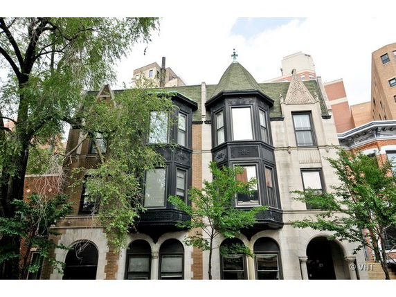 Front view of an ornate multi-story building with bay windows and green roof.
