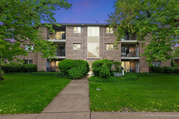 Front view of a three-story brick apartment building with balconies.