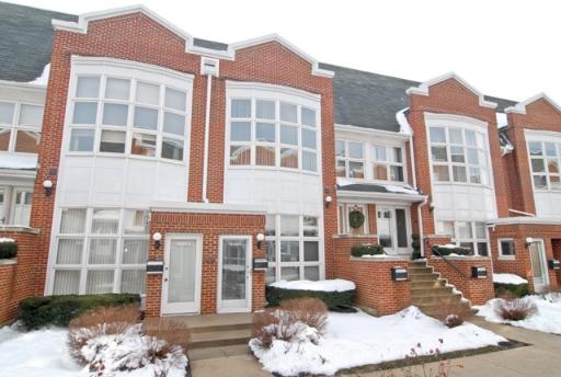 Front view of a row of two-story brick townhouses with large windows.