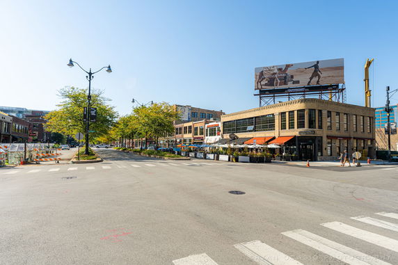 Street view of a building with large windows and an outdoor seating area.