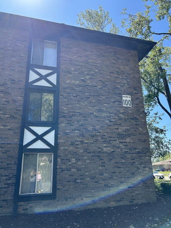 Front view of a brick building with windows and a sign indicating 'Building No 100'.