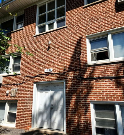 Front view of a brick residential building with multiple windows and a double door entrance.