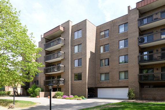 Front view of a multi-story apartment building with balconies and brick exterior.