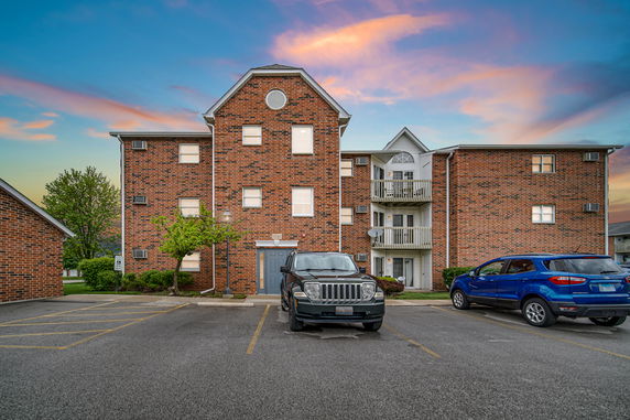 Front view of a brick multi-story building with parking area.