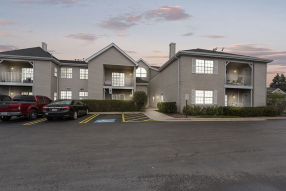 Front view of a two-story residential building with balconies and parking area.